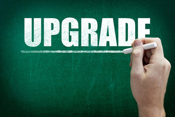 Hand writing the text UPGRADE on the blackboard