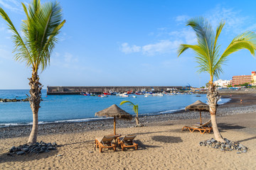 Palm trees on black sand volcanic beach in San Juan port, Tenerife island, Spain