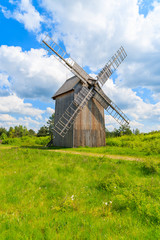 Old wooden windmill on green field in spring landscape of Tokarnia village, Poland