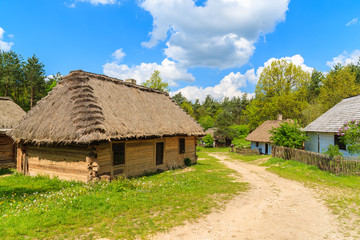 Fototapeta na wymiar Old traditional houses with straw roofs in Tokarnia village on sunny spring day, Poland
