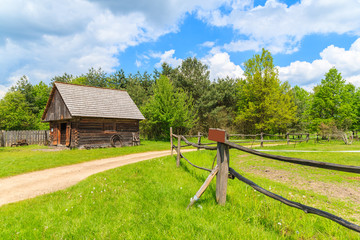 Rural road and wooden pasture fence in Tokarnia village on sunny spring day, Poland
