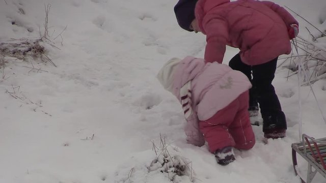 children climb up a snowy hill mom helps