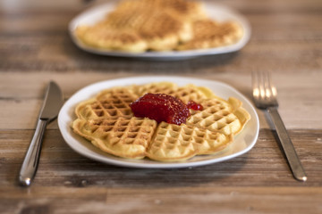 Eating Homemade waffles on white plate with red strawberry jam jelly