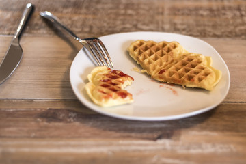 Eating Homemade waffles on white plate with red strawberry jam jelly