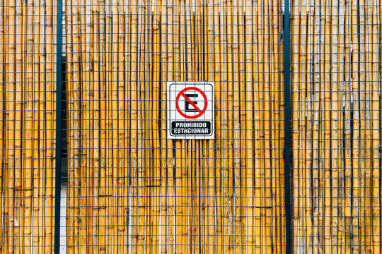 Black iron lattice with vertical rods and sign "No Parking" in Spanish