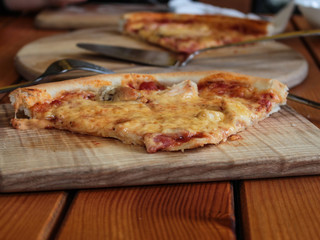  Piece of pizza on the table (on a wooden cutting board)