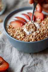 Close-up on a blue bowl with breakfast with oat flakes, yogurt and pieces of red plum. Selected focus.