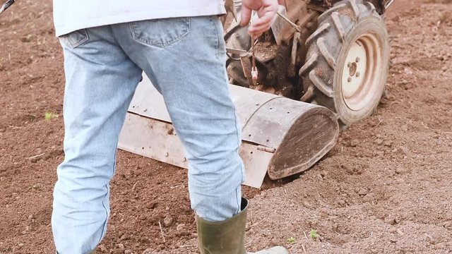 Farmer plowing the field with rototiller. 