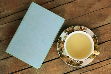 Tea Cup with Flower Pattern and Book on Wooden Background