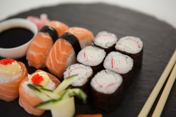 Set of assorted sushi served on black stone slate with soy sauce