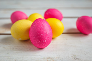 Easter background with yellow and pink eggs . Top view with copy space . Easter eggs on rustic wooden planks