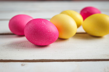 Easter background with yellow and pink eggs . Top view with copy space . Easter eggs on rustic wooden planks