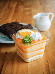 orange cake topped with piece of orange in plastic cup