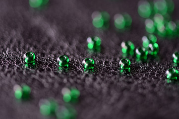 Transparent green seed beads on a dark leather background