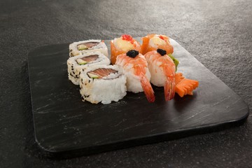 Uramaki and nigiri sushi served in black stone slate