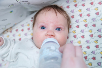 A girl child drinks water from a bottle.