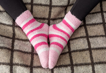 Woman feet in warm winter socks heated under blanket