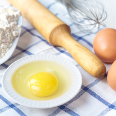 Eggs, flour and various ingredients and utensils lkx cooking homemade cakes on the white tablecloth in blue cage concept of domestic supply