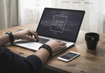 User with Smartphone and Laptop on Desk