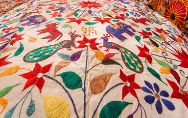 Beautiful birds and animals on surface of vintage textile colorful bedspread. Old asian market design.