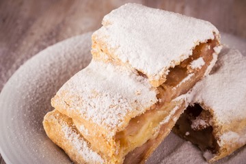 Detail of Two slices of apple strudel with powder sugar on white saucer