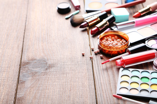 Different makeup cosmetics on brown wooden table