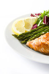 Grilled salmon fillet with asparagus and salad in plate isolated on white background
