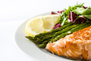 Grilled salmon fillet with asparagus and salad in plate isolated on white background

