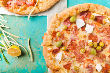 Spring pizza. Salami pizza. Pizza salami on a turquoise abstract background. Two pizzas. Copyspace