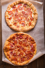 Rustic pizza with salami, mozzarellabasil top view with copy space. Two pizzas on a wooden table. Pizza salami on wooden background