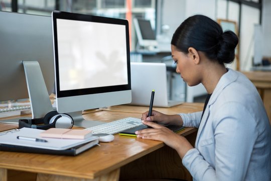 Female graphic designer using graphics tablet at desk