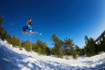 Naklejka na ściany i meble Flying snowboarder in the mountains