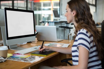Female graphic designer using graphics tablet at desk