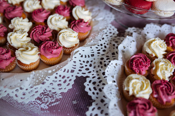 Beautiful multi colored decorated baked sweet tasty candy bar dessert party with happy people around, catering banquet table. macaroons