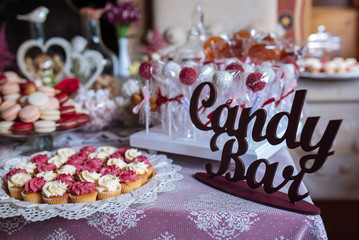 Beautiful multi colored decorated baked sweet tasty candy bar dessert party with happy people around, catering banquet table. macaroons