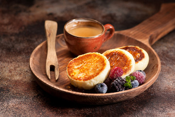 Cottage cheese pancakes syrniki with berries,  honey and cup coffee