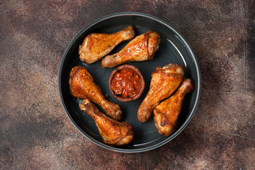 Fried grilled chicken legs with spicy sauce on a brown rusty texture