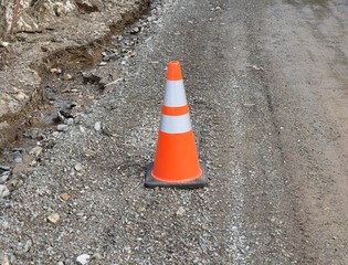 Orange safety cone on road near washout.