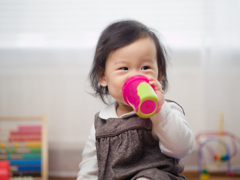 baby girl drinking water using a cup