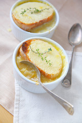 Overhead view of small bowls of onion soup with toasted cheese and fresh thyme topping