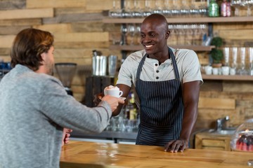 Waiter serving coffee to male customer