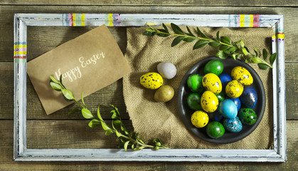 Easter colored eggs in a bowl on a wooden background