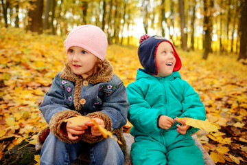 Brothers and sister playing outside in Autumn leaves.