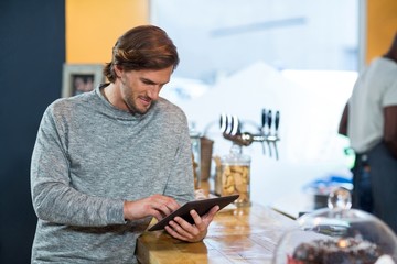 Young man using digital tablet at counter