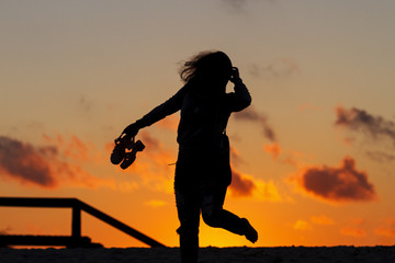 girl silhouettes and sandals on the beach