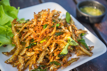 fried fish and cucumber with sauce on wood table.