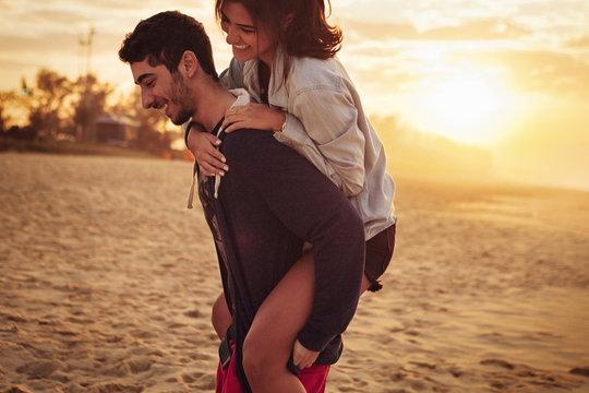 Man giving piggyback ride to his girlfriend on beach