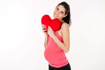 Portrait of a pretty pregnant woman with heart shaped pillow
