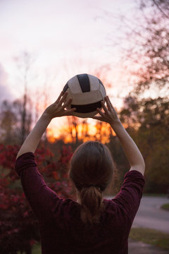 Teenage boy throwing ball at sunset