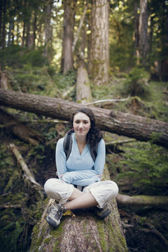 Portrait of young woman sitting on tree